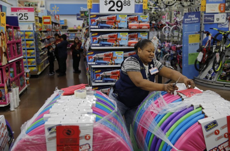 In this Nov. 27, 2019, file photo Balo Balogun labels items in preparation for a holiday sale at a Walmart Supercenter in Las Vegas. On Friday, Dec. 6, the U.S. government issues the November jobs report. (AP Photo/John Locher, File)