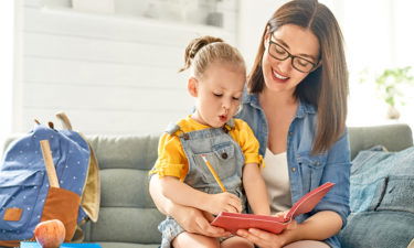 mother and her daughter are writing in notebook.