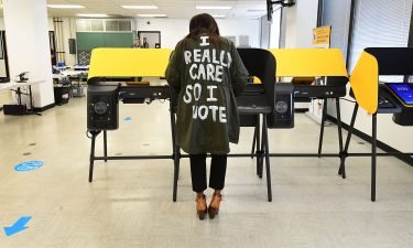 Wearing a coat reading "I Really Care So I Vote" written on the back