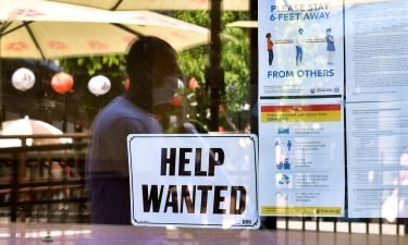A 'Help Wanted' sign is posted beside Coronavirus safety guidelines in front of a restaurant in Los Angeles