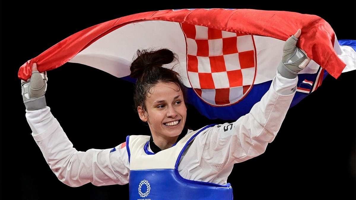 Matea Jelic smiles and raises the flag of Croatia behind her in celebration