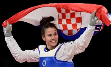 Matea Jelic smiles and raises the flag of Croatia behind her in celebration