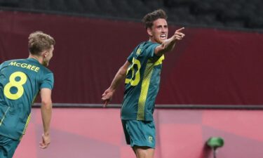 An Australian soccer player points in the direction of the camera