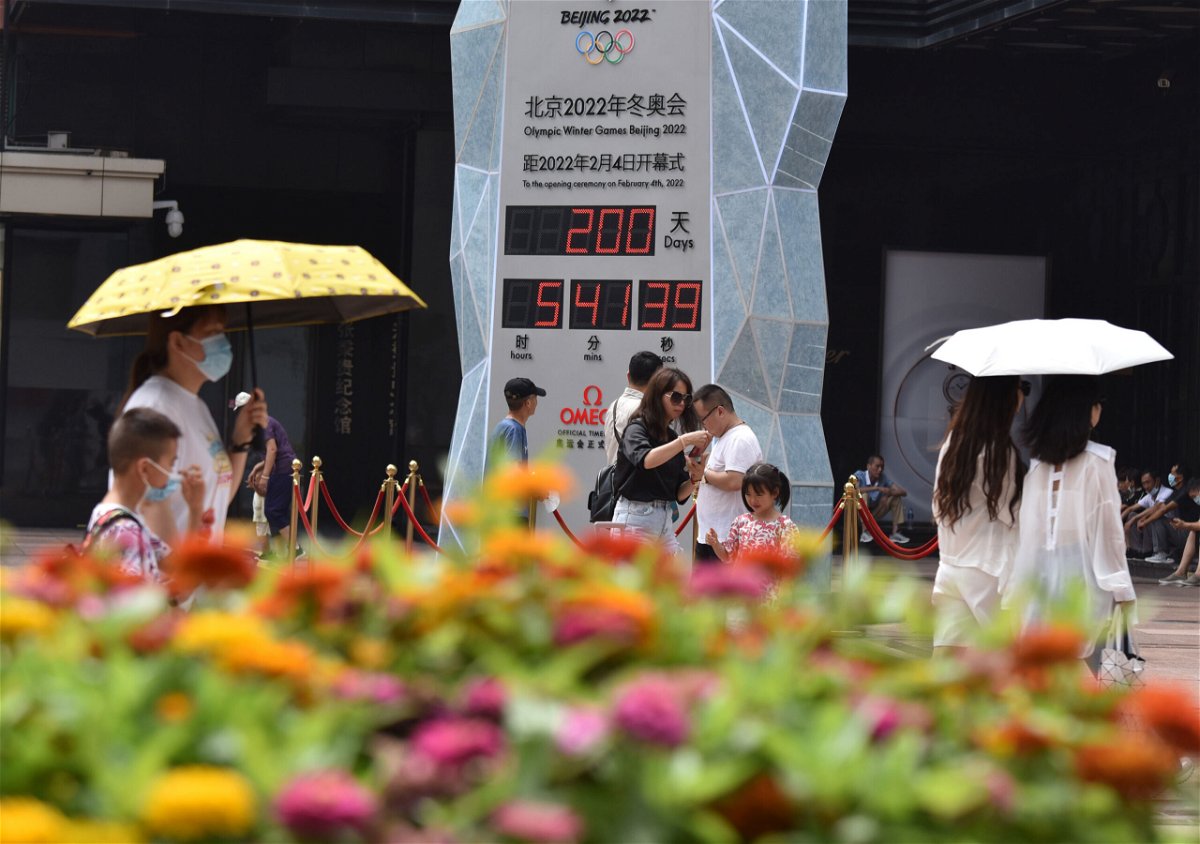 <i>Sheldon Cooper/SOPA Images/LightRocket/Getty Images</i><br/>People wearing face masks walk past the countdown clock showing 200 days to the 2022 Olympic Winter Games.