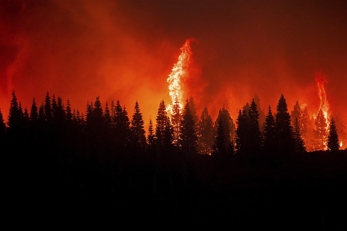 Flames from the Dixie Fire crest a hill in Lassen National Forest.