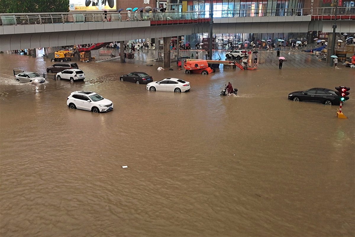 <i>STR/AFP/Getty Images</i><br/>People stranded in flood waters along a street following heavy rains in Zhengzhou