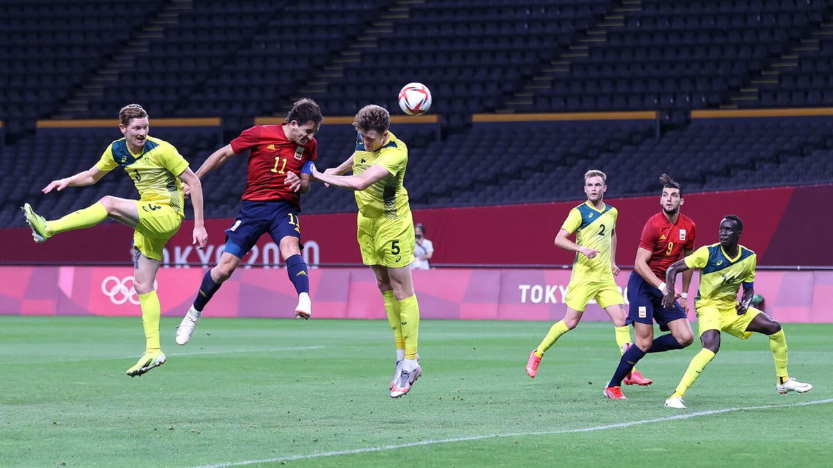 A Spanish soccer player and an Australian soccer players jump in the air after heading the ball