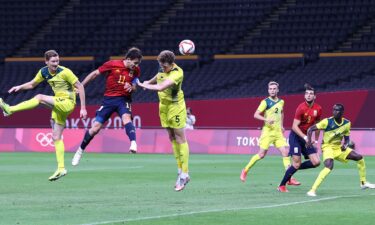 A Spanish soccer player and an Australian soccer players jump in the air after heading the ball