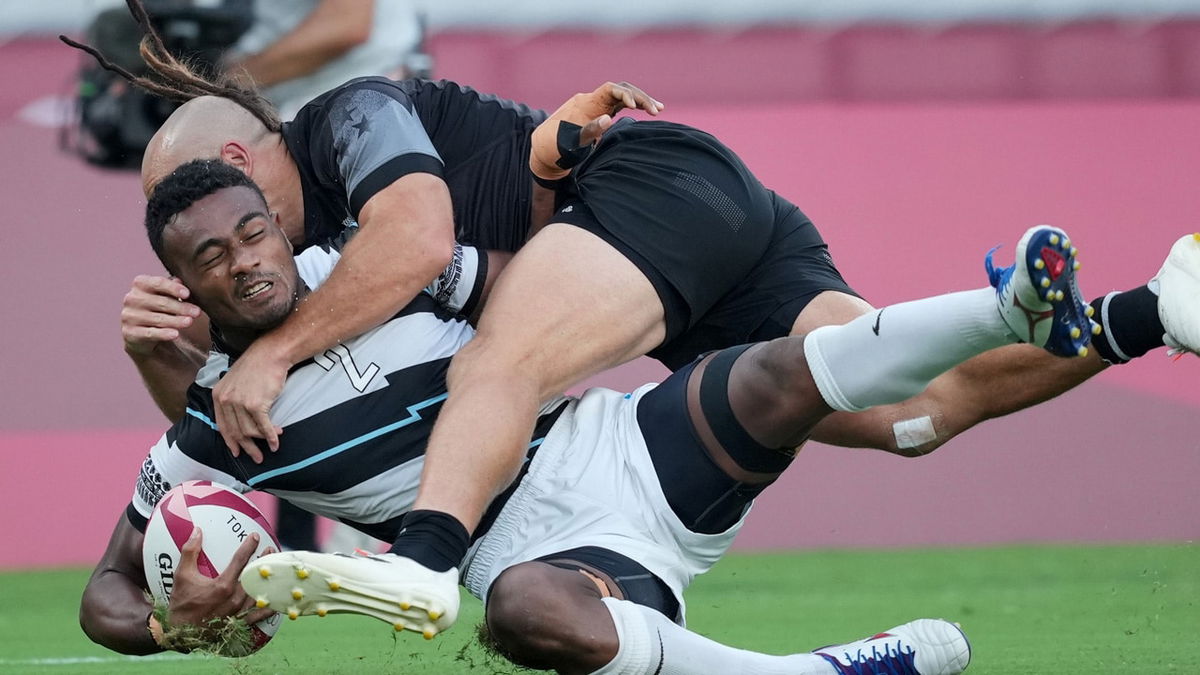 Two rugby players go down after a tackle