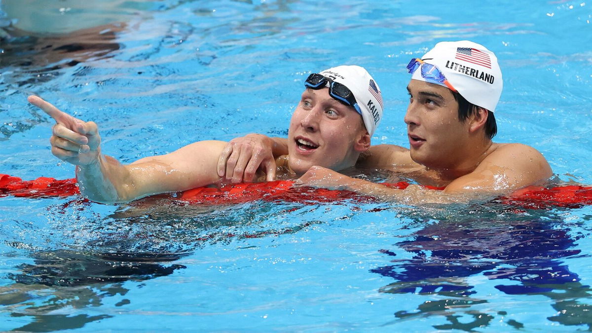 Two swimmers look on from a pool