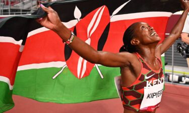 Kenya's Faith Kipyegon celebrates with her national flag after winning the gold medal in the women's 1500m final during the Tokyo 2020 Olympic Games