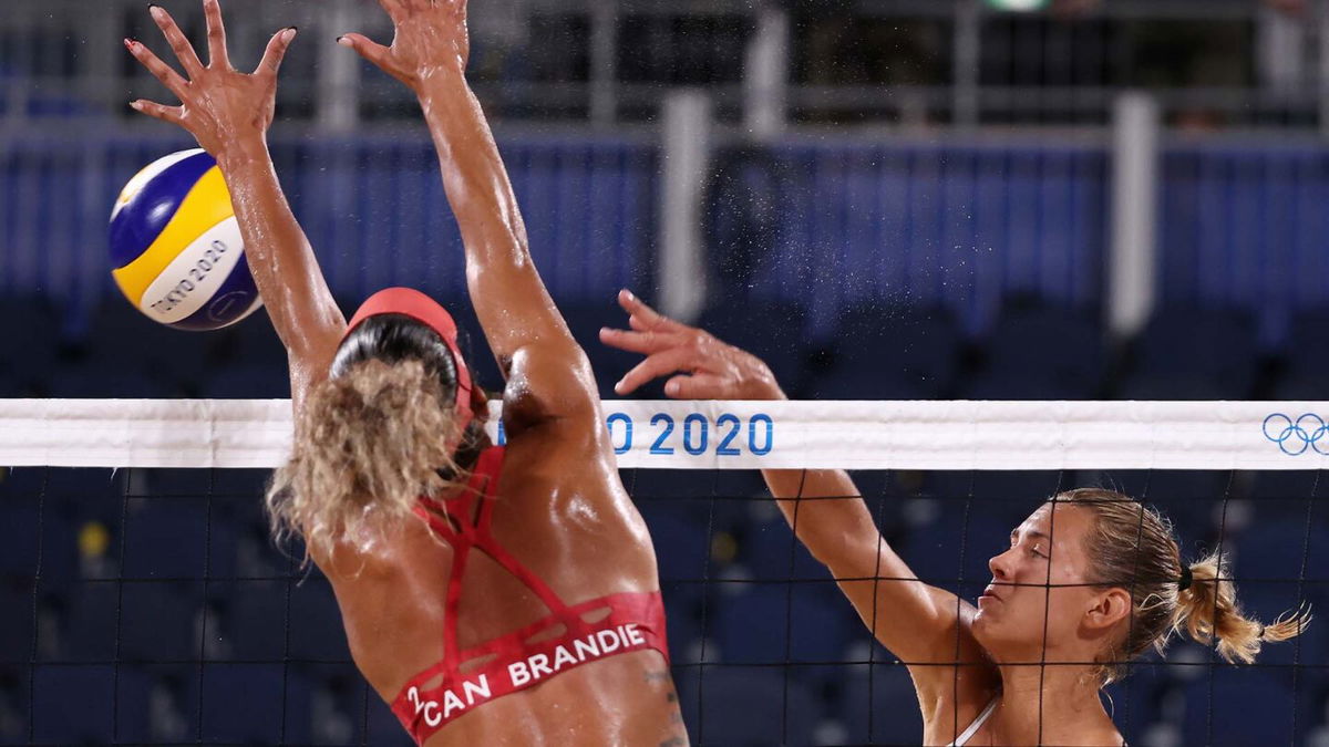 Member of the Canadian beach volleyball team blocks a shot by Latvia