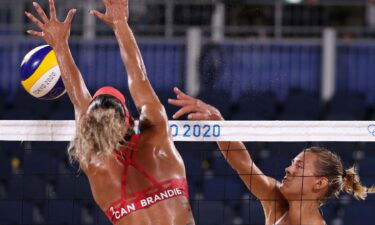 Member of the Canadian beach volleyball team blocks a shot by Latvia