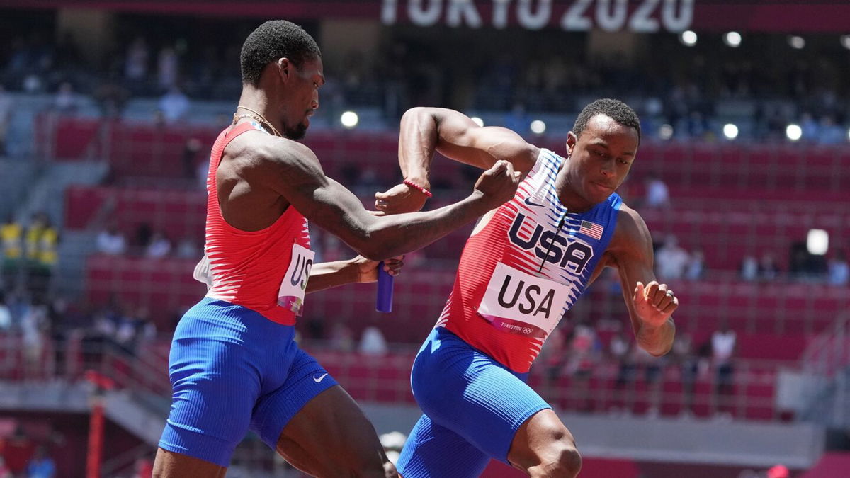 Fred Kerley and Ronnie Baker pass the baton while running on the track