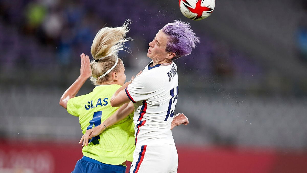 Purple-haired Megan Rapinoe goes up for a header against Sweden's Hanna Glas