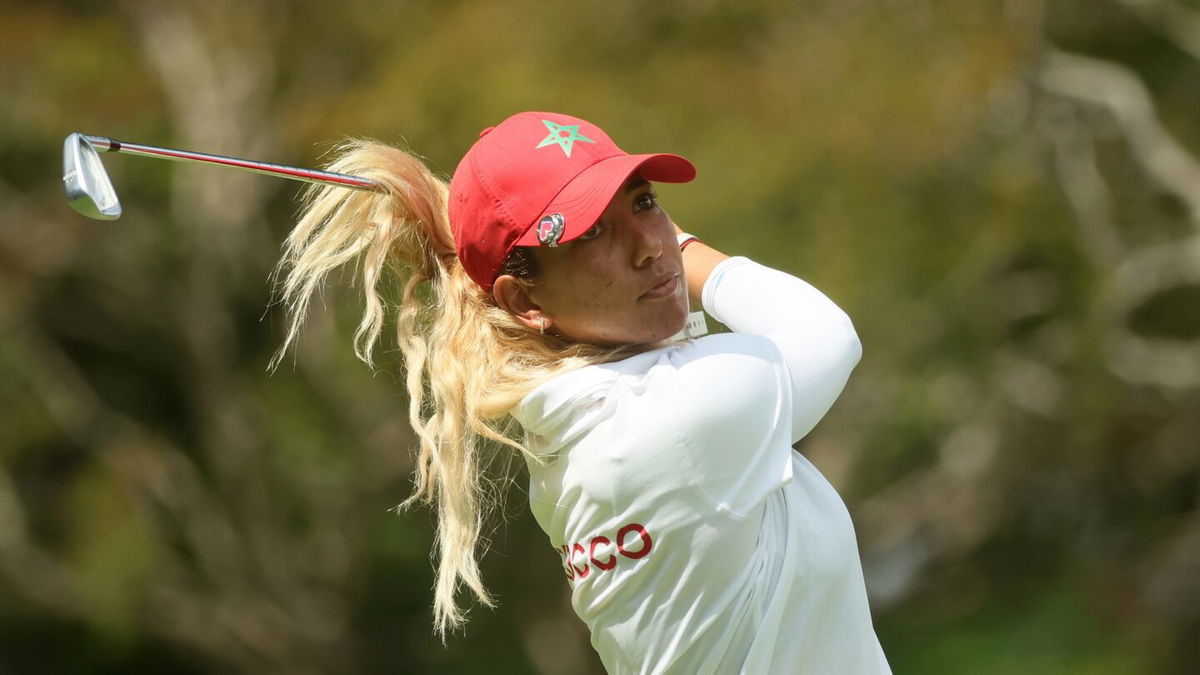 Maha Haddioui of Morocco's iron is caught under her blonde hair after a shot in first round action