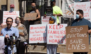 People from a coalition of housing justice groups hold signs protesting evictions during a news conference outside the Statehouse
