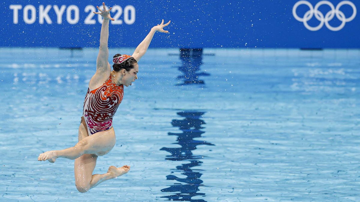 A member of China's artistic swim team leaps out of the water.