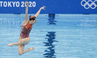 A member of China's artistic swim team leaps out of the water.