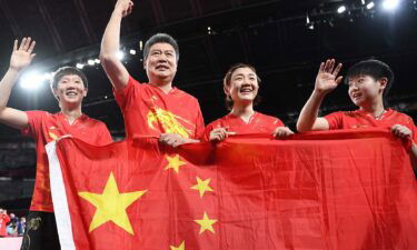 The Chinese Women's Table Tennis Team celebrates with their flag after their gold medal win