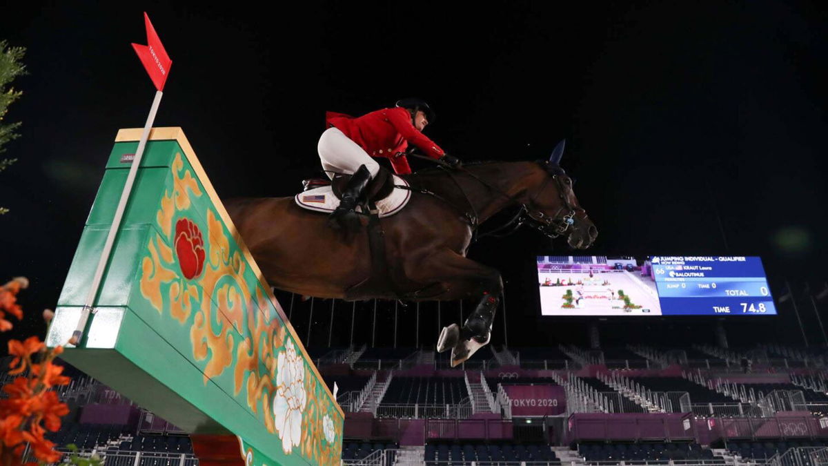 Low angle of Laura Kraut and her horse jumping over a green and yellow wall