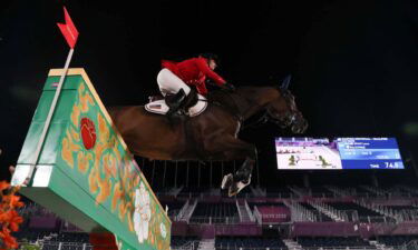 Low angle of Laura Kraut and her horse jumping over a green and yellow wall