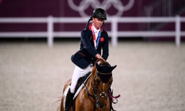 Ben Maher pats his horse on the way to the victory ceremony