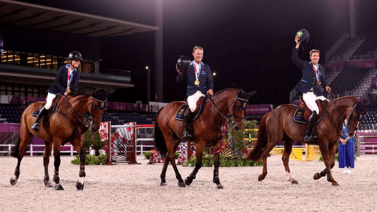 Three Swedish riders smile on their horses and wear medals