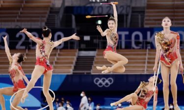 A rhythmic gymnastics team executes jumps and throws.
