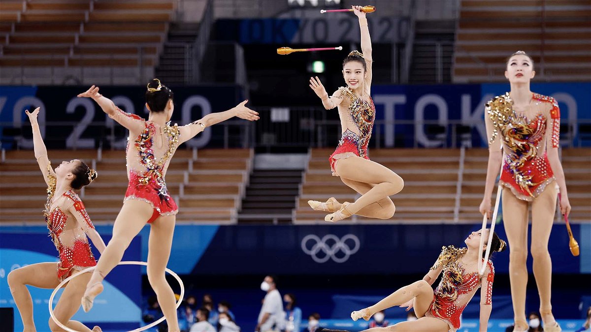 A rhythmic gymnastics team executes jumps and throws.