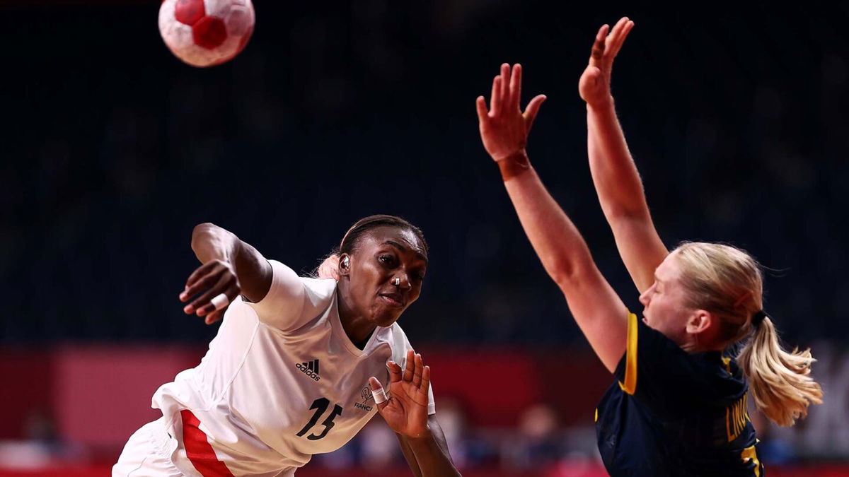 Member of the French handball team hurls the ball while a member of the Swedish handball team attempts to block