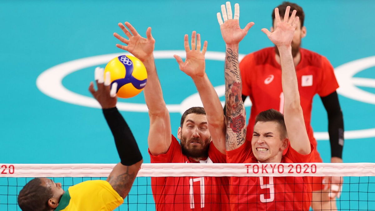 Maxim Mikhaylov #17 of Team ROC and Ivan Iakovlev #9 defend against the strike by Yoandy Leal Hidalgo #9 of Team Brazil during the Men's Semifinals volleyball on day thirteen of the Tokyo 2020 Olympic Games