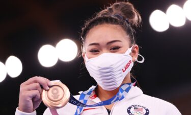 Suni Lee poses with the bronze medal she won in the uneven bars event final