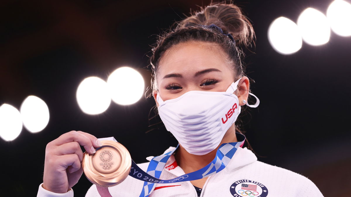 Suni Lee poses with the bronze medal she won in the uneven bars event final