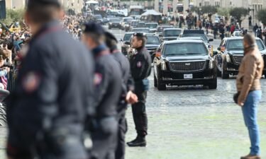 Police officers stand by as the motorcade of President Joe Biden arrives across the Via della Conciliazione in Rome leading to the Vatican on Friday