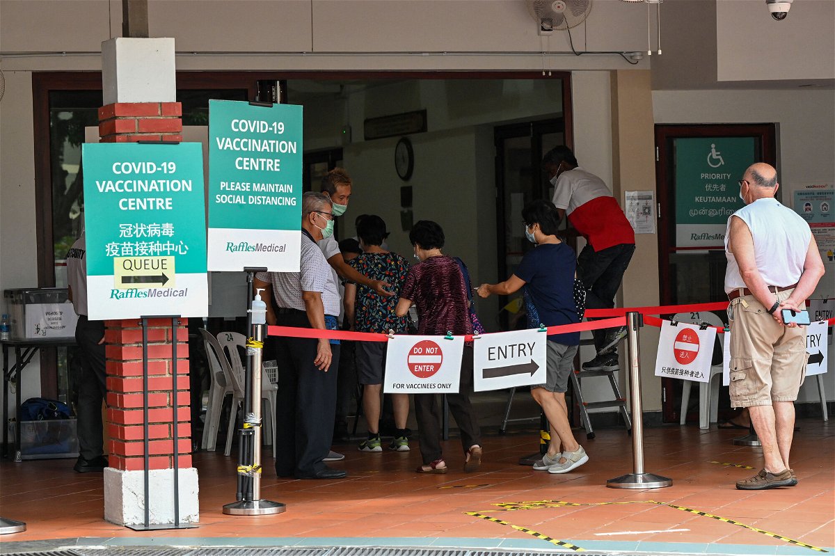 <i>Roslan Rahman/AFP/Getty Images</i><br/>People enter a Covid-19 vaccination center in Singapore on October 7.