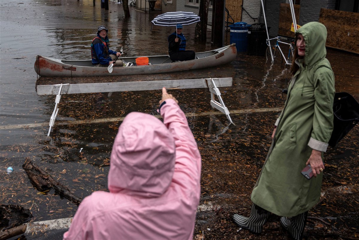 <i>Andrew Caballero-Reynolds/AFP/Getty Images</i><br/>A woman points at two people paddling through flood water in a canoe in Old Town Alexandria