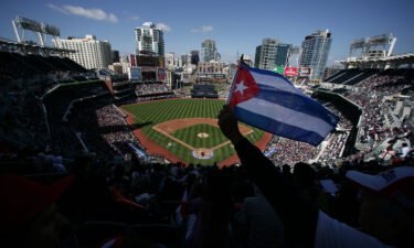 Cuba's state media on Sunday lashed out after nearly a dozen Cuban baseball players defected in Mexico -- believed to be one of the country's largest and most embarrassing known incidents of mass defection in years. A Cuban flag is held at Petco Park in San Diego