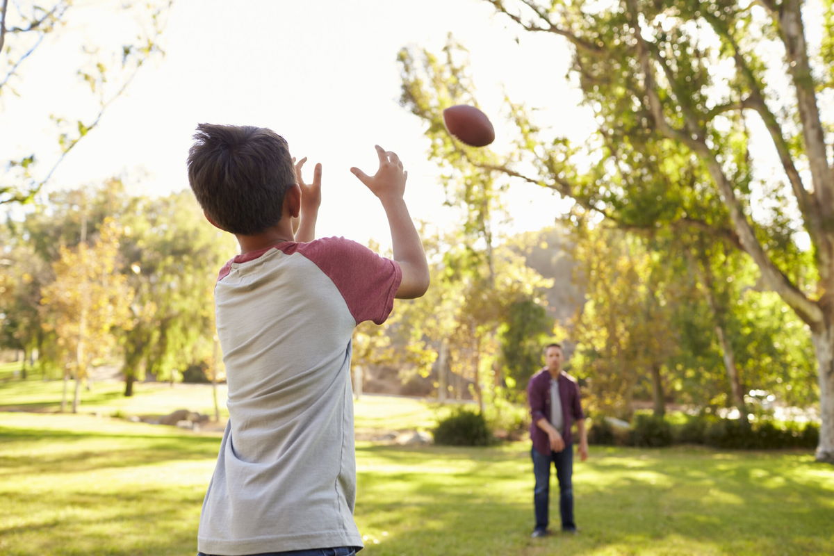 <i>Adobe Stock</i><br/>This stock photo shows a father and son tossing a football.