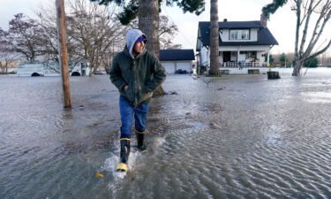 Benjamin Lopez steps from floodwater surrounding his parents home Monday in Sedro-Woolley