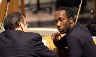 Rudy Guede (R) talks to his lawyer's assistant in Perugia courthouse on November 18