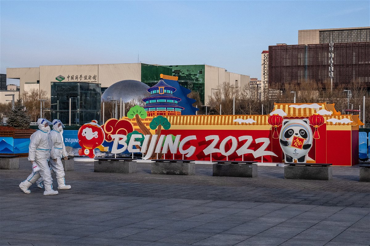 <i>Carl Court/Getty Images</i><br/>People in personal protective kits walking past a Winter Olympics display on Wednesday in Beijing.
