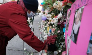 People visit a memorial set up for the victims outside the apartment building where a five-alarm fire took place on January 14