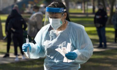 Medical assistant Leslie Powers carries swab samples collected from people to process them on-site at a Covid-19 testing site Thursday in Long Beach