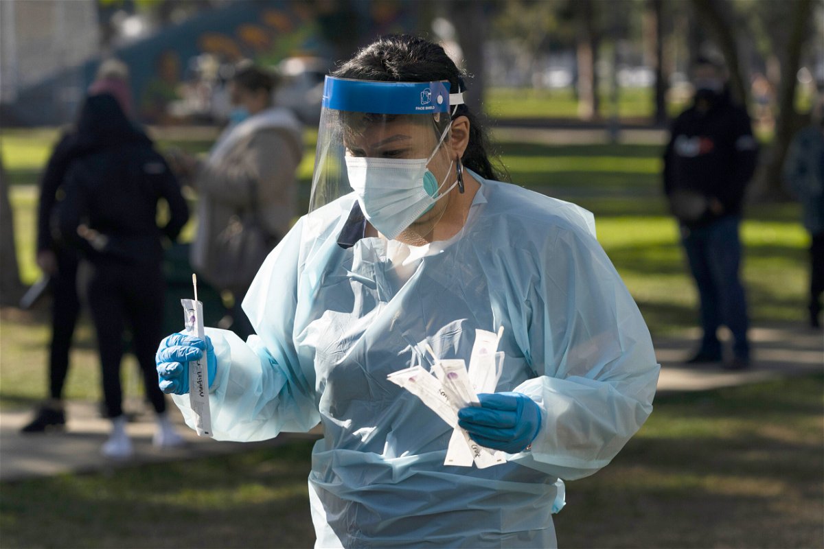 <i>Jae C. Hong/AP</i><br/>Medical assistant Leslie Powers carries swab samples collected from people to process them on-site at a Covid-19 testing site Thursday in Long Beach