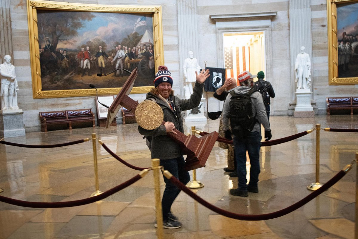<i>Win McNamee/Getty Images</i><br/>Adam Johnson carries the lectern of Speaker of the House Nancy Pelosi through the Rotunda of the US Capitol Building after a pro-Trump mob stormed the building on January 6