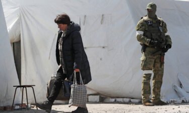 A woman carries bags as evacuees
