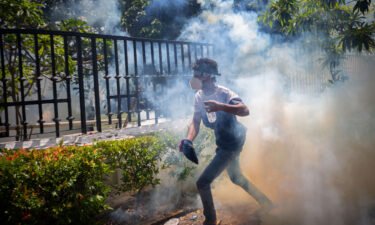 A protester runs for cover from a tear gas canister during a protest in Colombo