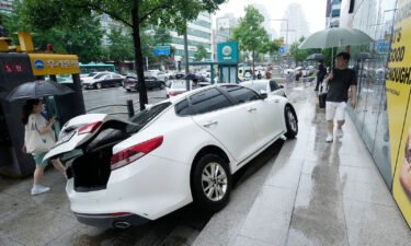 A vehicle is damaged on the sidewalk after floating in heavy rainfall in Seoul