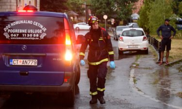 A firefighter walks by a hearse on the site of the attack in Cetinje